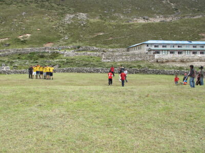 altitude sickness Nepal trekking — porters and trekkers playing soccer at 14,000 feet in the Himalayas