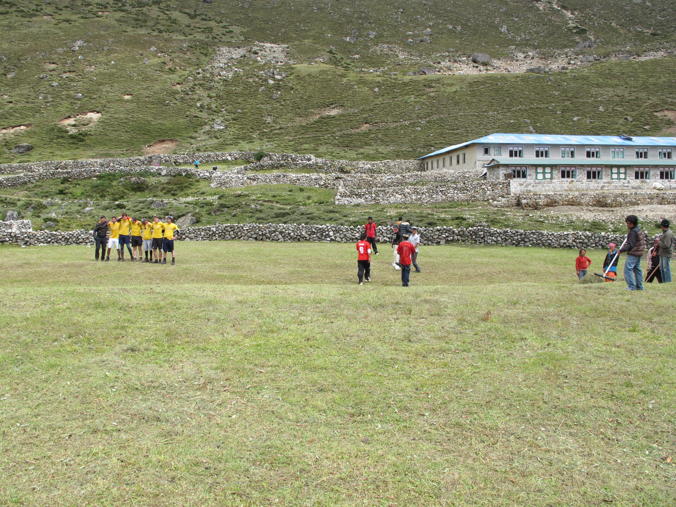 altitude sickness Nepal trekking — porters and trekkers playing soccer at 14,000 feet in the Himalayas